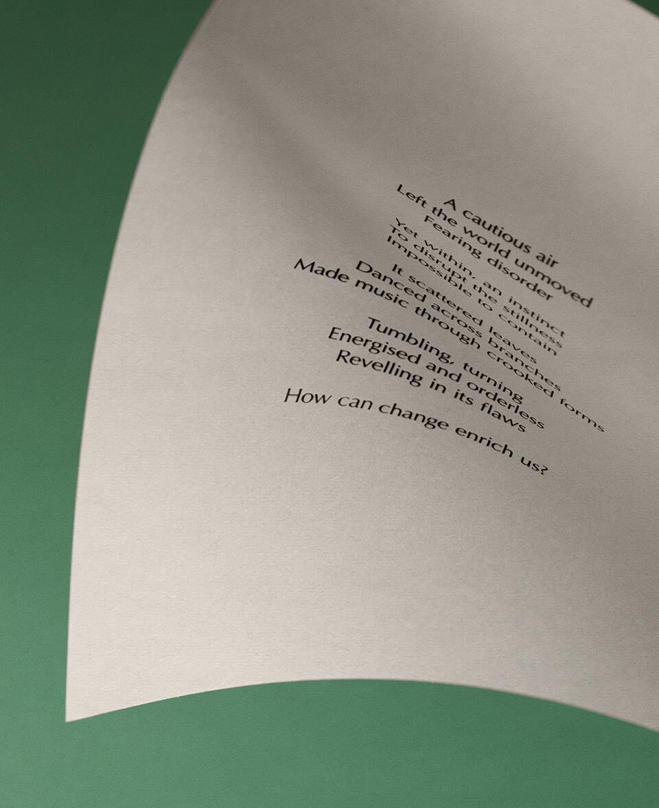 Papel crema curvado con texto poetico sobre un fondo verde apagado.