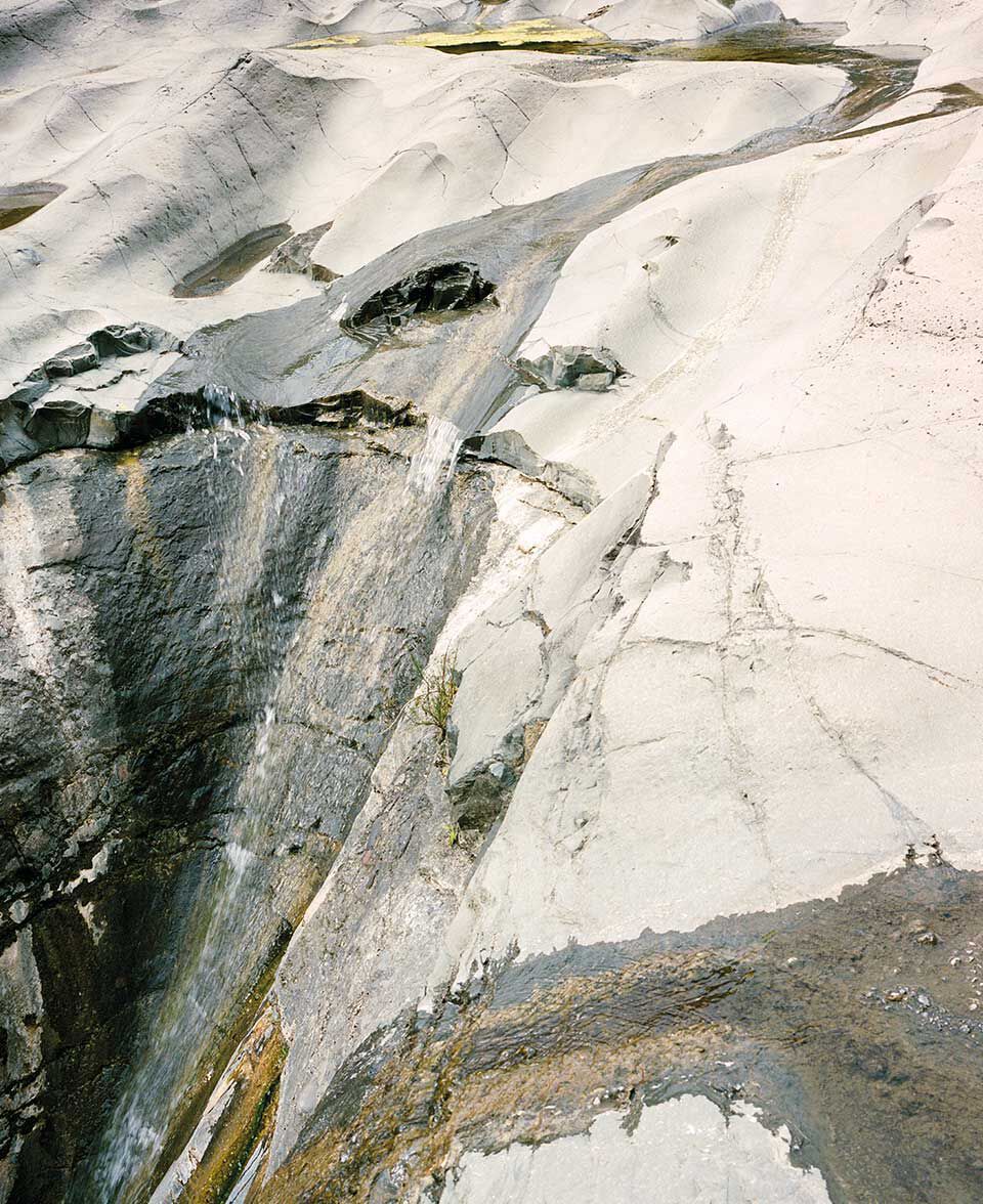 Palida pared rocosa erosionada, con patrones minerales fluidos y estrias.