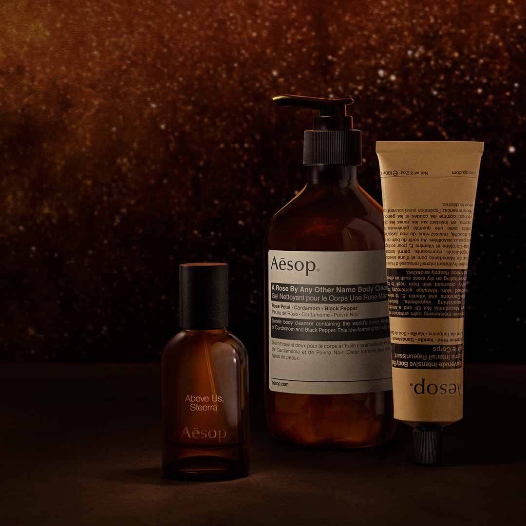 Frasco de Aesop Above Us, Steorra con dispensador y tubo sobre un fondo marron moteado de tonos calidos.