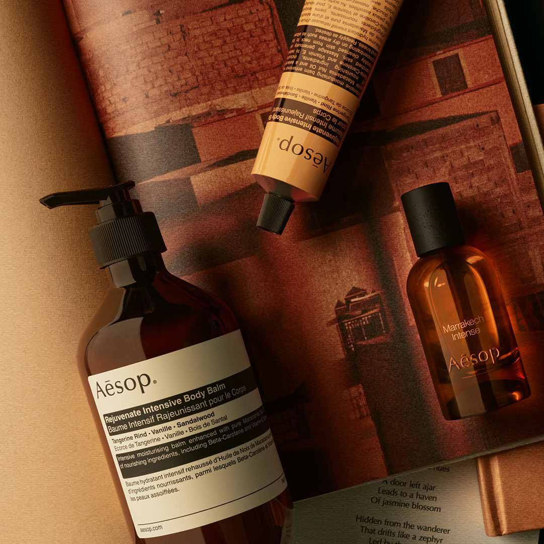 Frasco de Aesop Marrakech Intense con dispensador y tubo amarillo, dispuestos sobre papeles de tonos calidos.