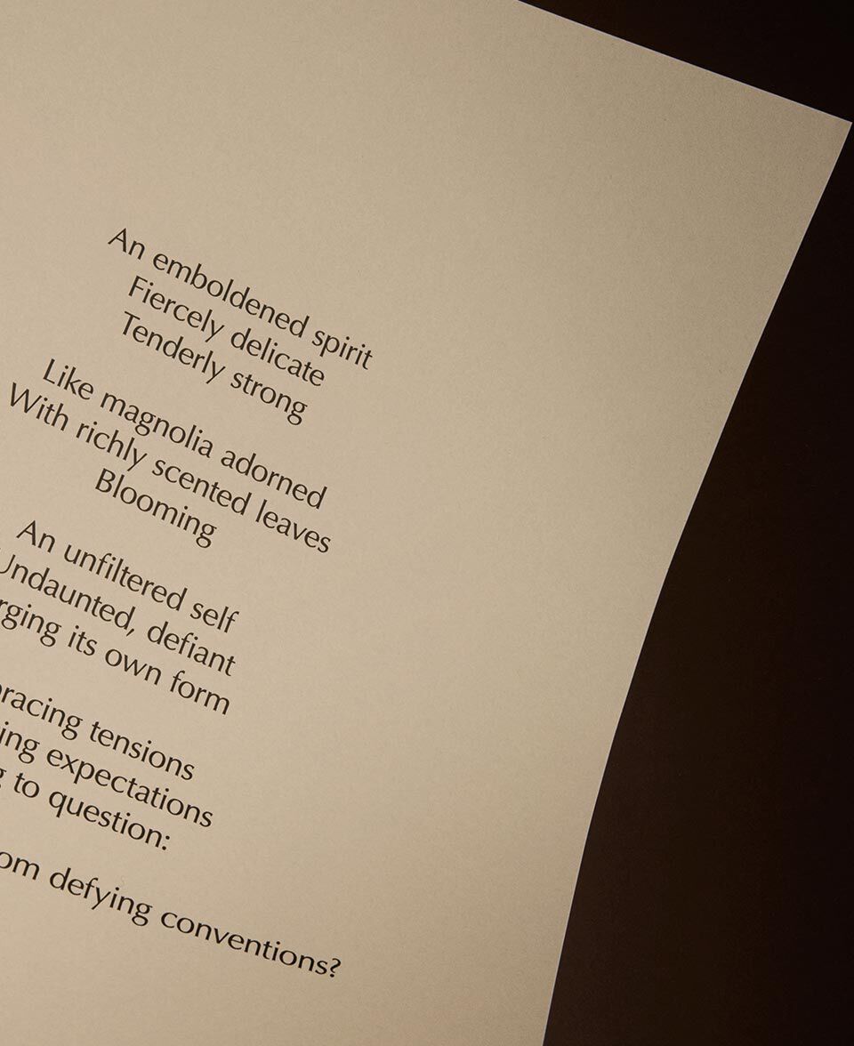 Texto de poema en una pagina color crema suavemente iluminada, sobre un fondo oscuro.