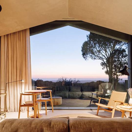 The view from inside a hotel room looking out over the mountains, dusk falling.