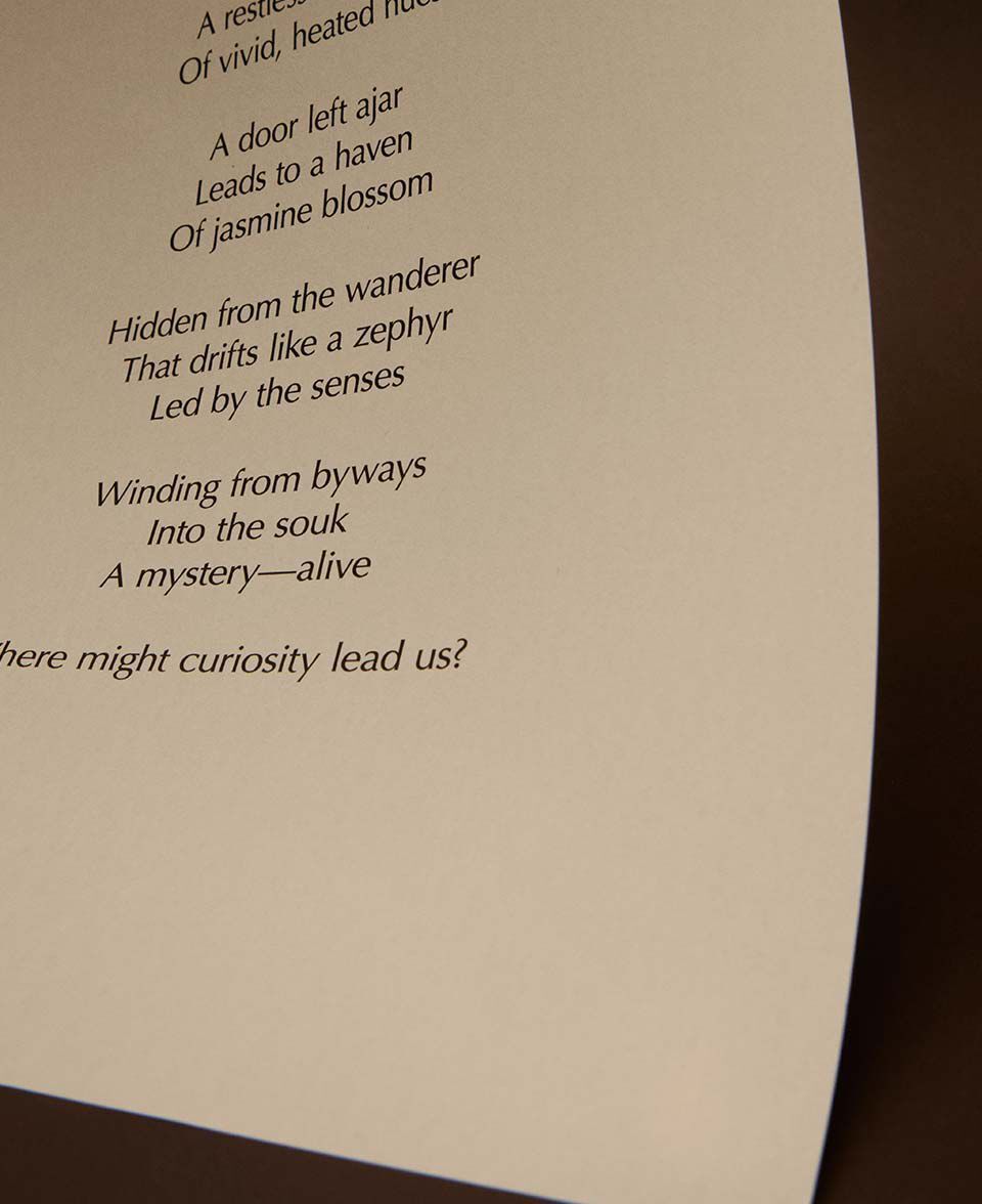 Primer plano de versos impresos de un poema sobre una hoja curva de papel color crema.