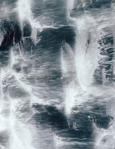 Superficie rocosa de color gris azulado oscuro, con vetas blancas similares a venas y una textura mineral rugosa, que forma un patron marmoleado de alto contraste.