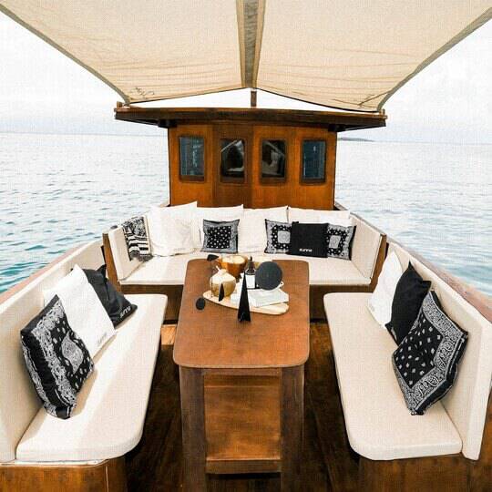 A boat out to water with cushioned bench seating and a canopy above providing shade.